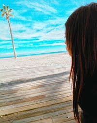 Rear view of woman on beach against sky