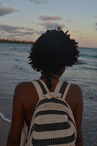 Rear view of woman standing on beach against sky