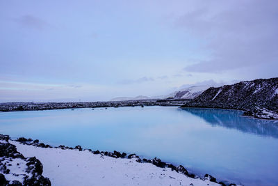 Scenic view of lake by snowcapped mountains against sky