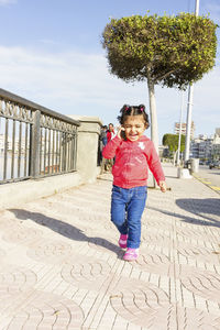 Happy girl talking on mobile phone on sidewalk