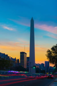 Illuminated skyscrapers against blue sky during sunset