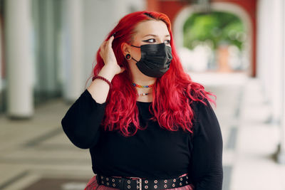 Portrait of young woman standing against red wall