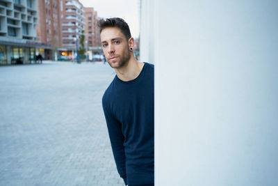 The modern man in casual clothes leaning against a wall