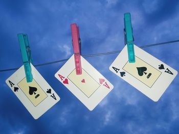 Low angle view of information sign hanging against blue sky