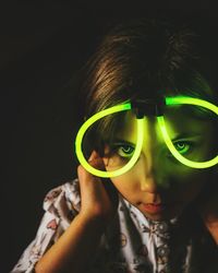 Close-up portrait of boy wearing sunglasses against black background