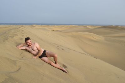 Shirtless man lying on shore at beach