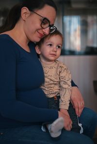 Pregnant mother holding her little toddler in a lap