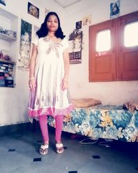 Portrait of young woman standing at home