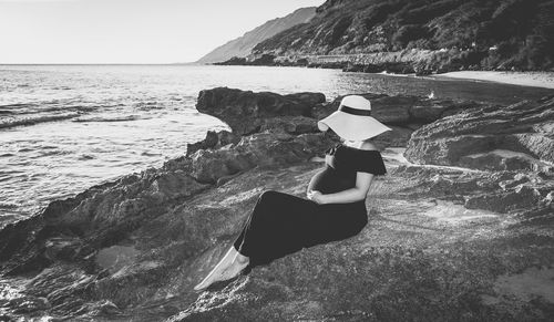 Rear view of woman standing on beach against clear sky