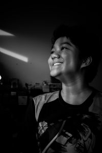 Side view of young man standing against black background