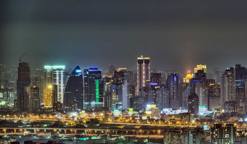 Illuminated cityscape against sky at night