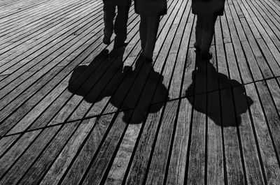 Low section of people walking on wooden floor