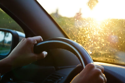 Cropped hands on steering wheel at morning