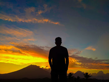 Rear view of silhouette man standing against orange sky