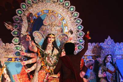 Rear view of people standing in illuminated temple