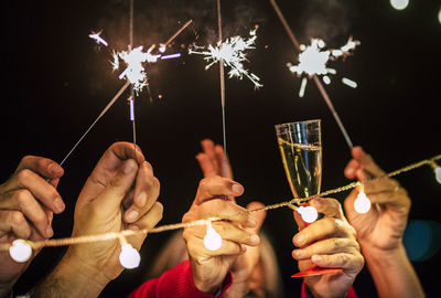 Cropped image of man holding sparkler at night