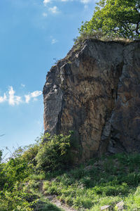 Low angle view of rock formation amidst trees against sky