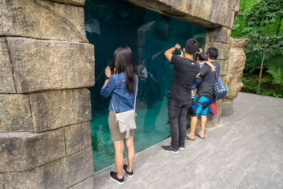 Rear view of people standing against wall