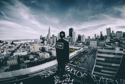 Rear view of man standing by buildings against sky