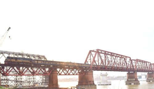 Low angle view of suspension bridge over river against clear sky