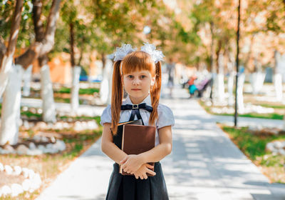 Funny charming little girl with books in her hands, on the first day of school or kindergarten.