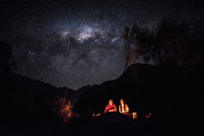 Silhouette people on mountain against sky at night