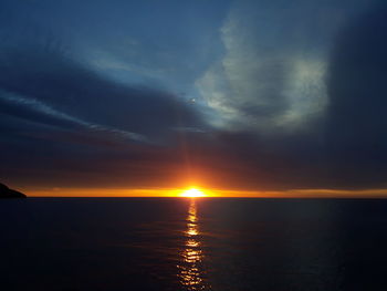 Scenic view of sea against dramatic sky during sunset