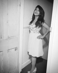 Portrait of smiling young woman standing against wall