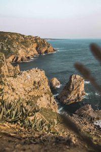 Rocks on shore by sea against sky