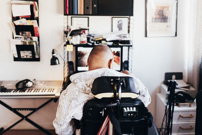 Rear view of disabled musician sitting on wheelchair in recording studio
