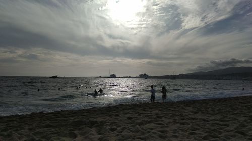 Silhouette people on beach against sky