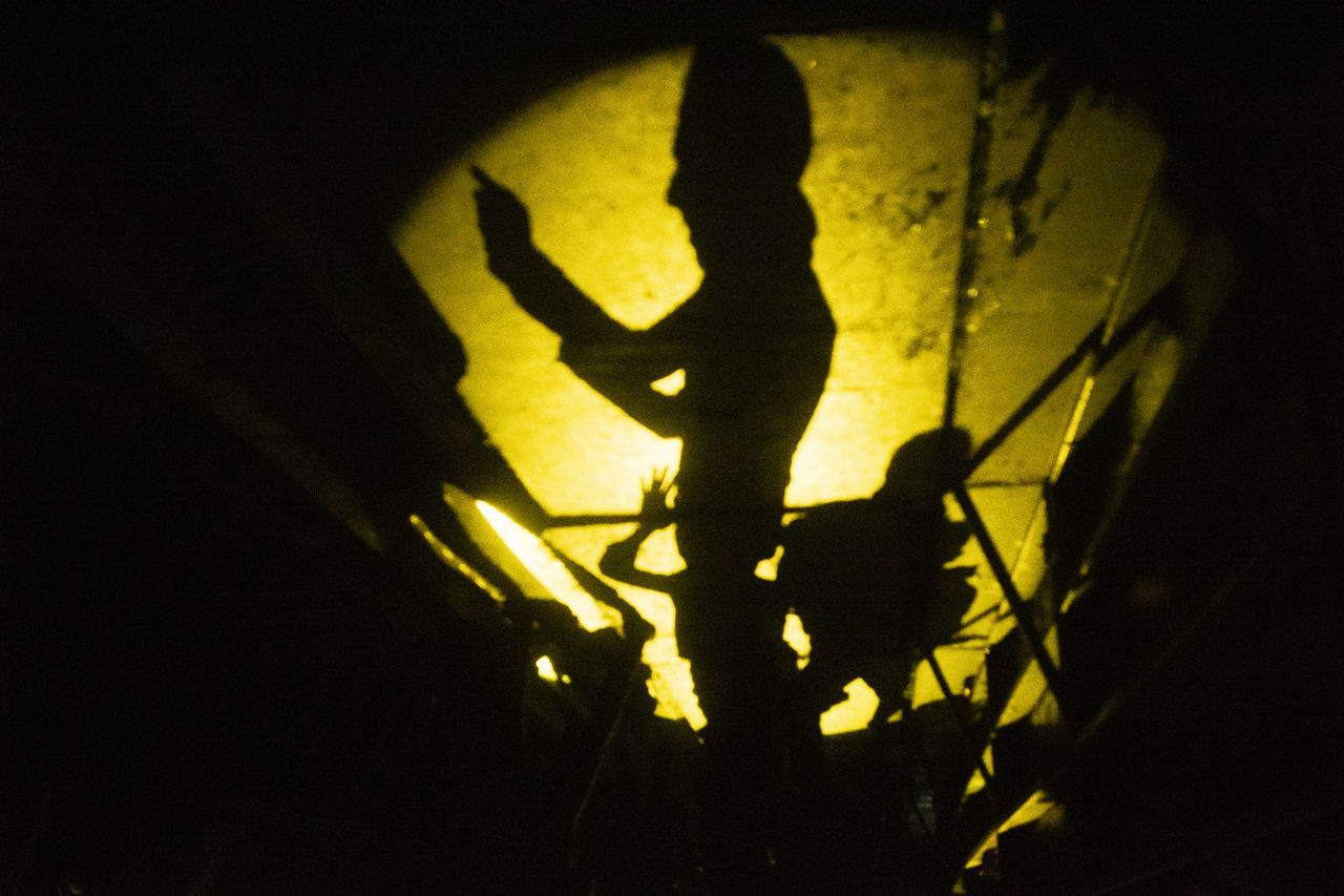 SHADOW OF PEOPLE WALKING ON ILLUMINATED WALL