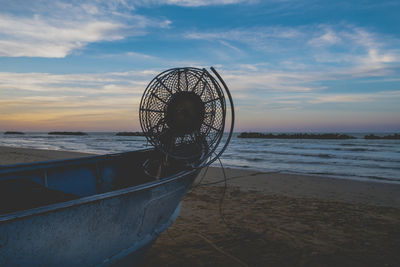 Ferris wheel on beach against sky during sunset