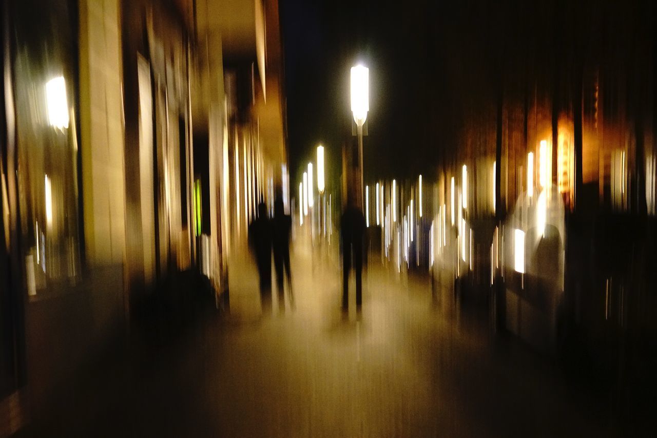 BLURRED MOTION OF MEN WALKING IN ILLUMINATED UNDERGROUND