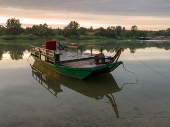 Boat moored in river against sky during sunset