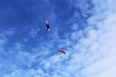 Low angle view of persons paragliding in blue sky. stock photo 