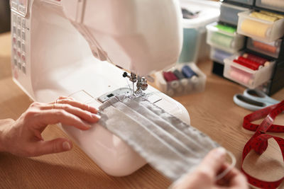 Woman hands using the sewing machine to sew the face mask