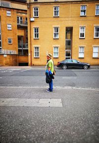 Full length of man riding motorcycle on road against building