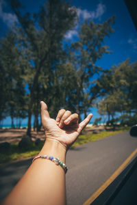 Cropped woman gesturing by window in car on road