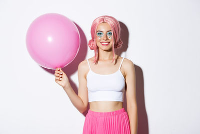 Portrait of woman with pink balloons against white background