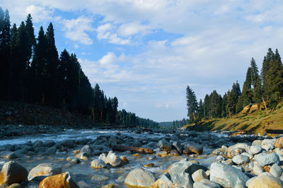 Rocks by river against sky