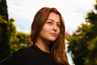 Portrait of beautiful young woman against sky