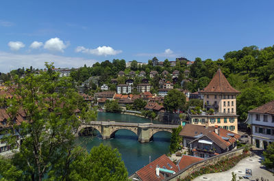 Arch bridge over river amidst buildings in city against sky