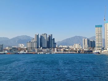 Sea by buildings against clear blue sky