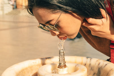 Asian tourist woman is drinking from public tap water.