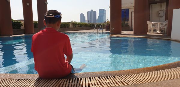 Rear view of man relaxing in swimming pool