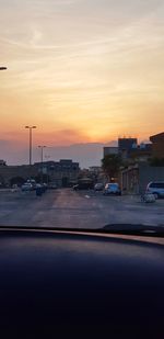 Cars on street against sky during sunset