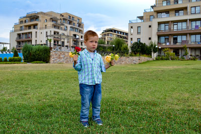 Life style portrait red-haired boy  in a park with flowers, cheerful childhood, summer  holidays