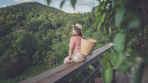 Woman carrying basket while sitting on railing