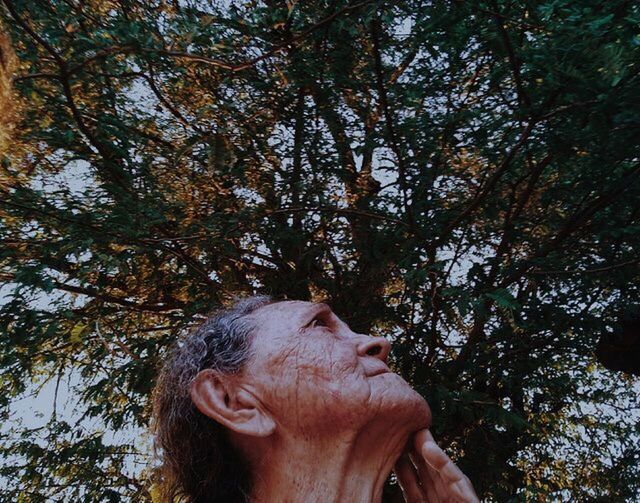 LOW ANGLE PORTRAIT OF YOUNG MAN AGAINST TREES